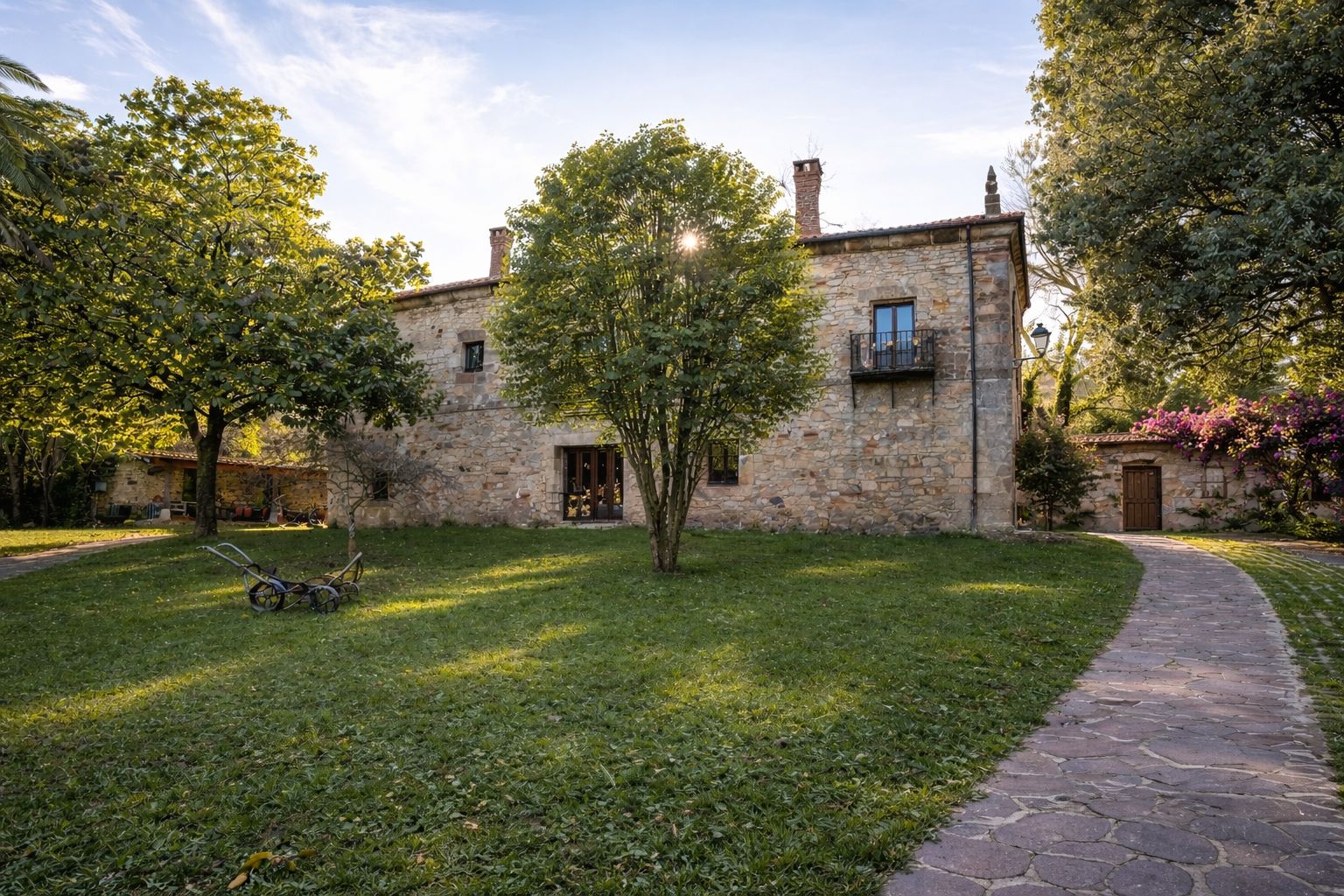 Fachada de Cabárceno Palacio desde el jardín, con el camino de entrada entre árboles